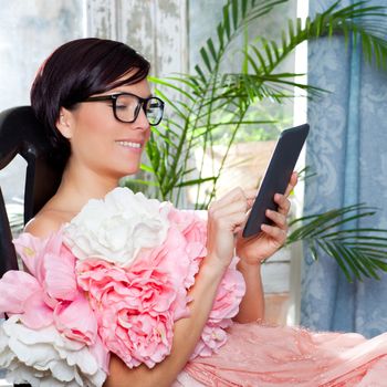 fashion woman and tablet ebook reading at home with spring pink flowers dress