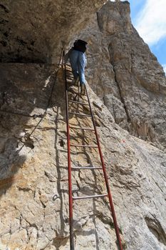 woman is climbing on metal ladder in Italian Dolomites