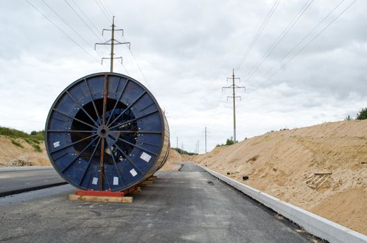 road building work and electricity line laying underground. huge high voltage cable reels power line construction site.