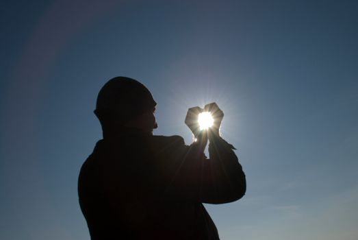 man holding a sun in his hands against the sky