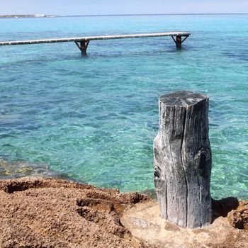 Formentera Illetes turquoise sea wooden pier aged trunk Illetas