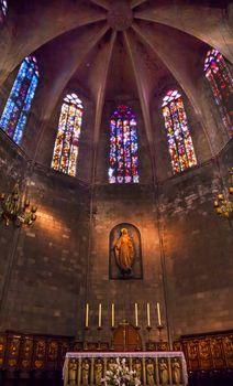 Stained Windows, Mary Statue, Altar and Crucifix in Old Stone Basilica, St Maria del Pi, Saint Mary of Pine Tree, in Barcelona, Spain. Saint Maria del Pi was founded in 987AD or earlier. One of the oldest churches in Barcelona.