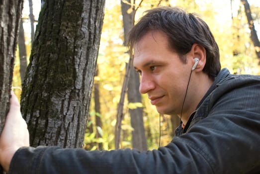 man with headphones standing near the tree