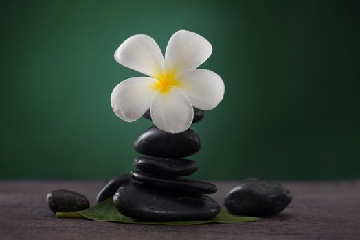 Stacked hot stones for massage spa and frangipani with green background

