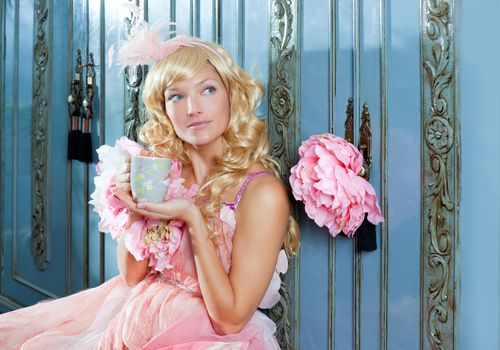 blond fashion princess woman drinking tea or coffee at home with vintage pink dress