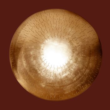 Asian brass gong golden round isolated on dark red