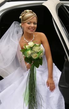The beautiful bride with a bouquet in the automobile
