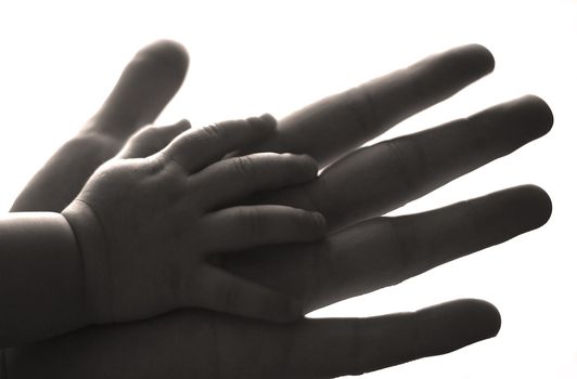 The image of hands of parents and the kid. b/w+sepia