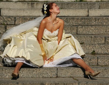 The beautiful bride sitting on a stone ladder