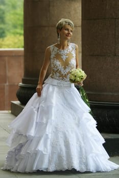 The beautiful bride with a bouquet at columns