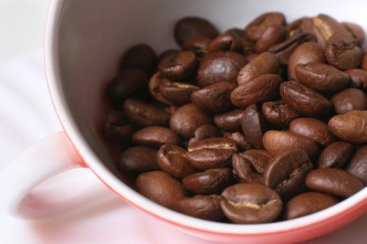 Grains of coffee in a white bowl. Macro-ring