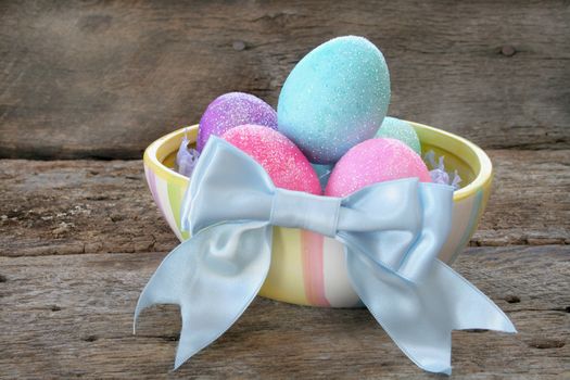 Colorful Easter eggs in a dish with a blue bow.