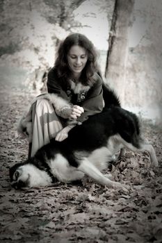 Lady in medieval dress and dog in the forest
