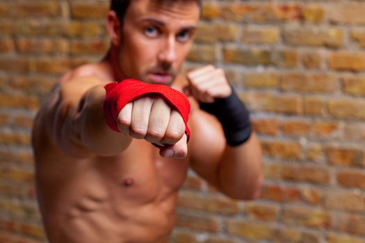 muscle boxer shaped man fist to camera on brickwall