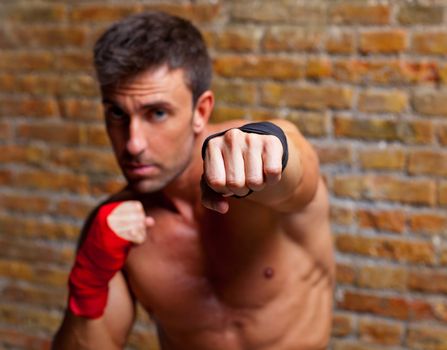 muscle boxer shaped man fist to camera on brickwall