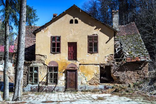 abandoned, ruined house in daylight against blue sky