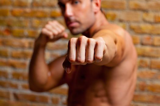 muscle boxer shaped man fist to camera on brickwall