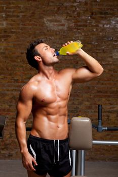 muscle shaped man at gym relaxed drinking energy drink