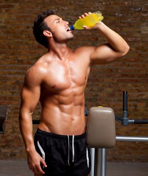 muscle shaped man at gym relaxed drinking energy drink