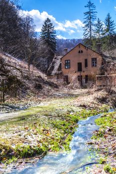 stream flowing next to a deserted house