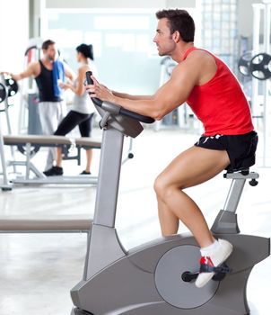 man on stationary bicycle at sport fitness gym interior
