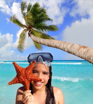 latin tourist girl holding starfish in tropical beach