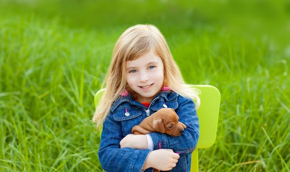 Blond kid girl with puppy pet dog sit in outdoor green grass