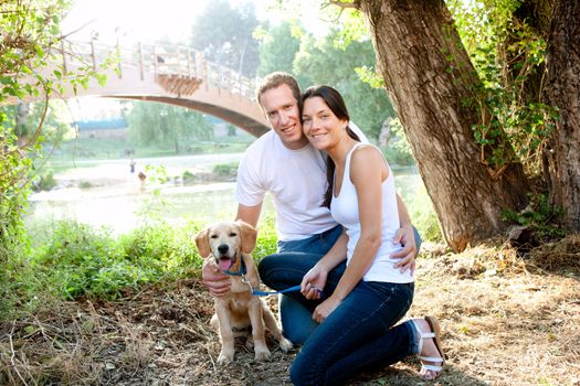 Couple in love with dog in outdoor river with bridge