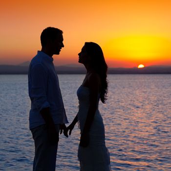 couple in love back light silhouette at lake orange sunset