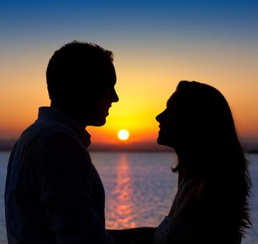 couple in love back light silhouette at lake orange sunset