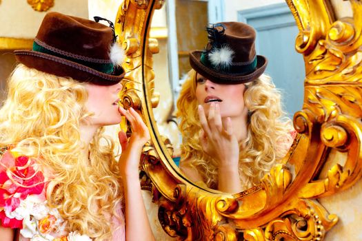 fashion blond woman with hat looking in baroque golden frame mirror