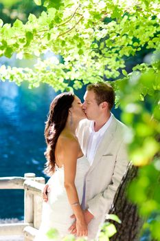 couple in love kissing in forest tree blue lake outdoors