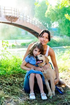daughter and mother with golden retriever dog in outdoor park