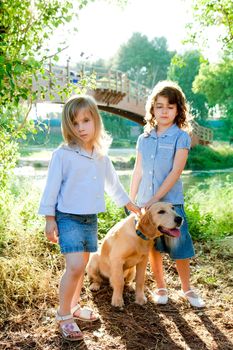 kid girls with Golden retriever puppy outdoor park river