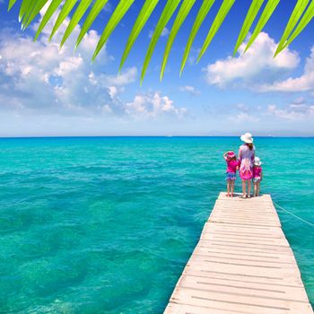 Daughters and mother in jetty on Formentera with turquoise sea