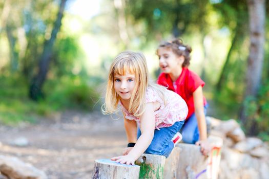 kid girls playing on trunks knee walking in forest nature
