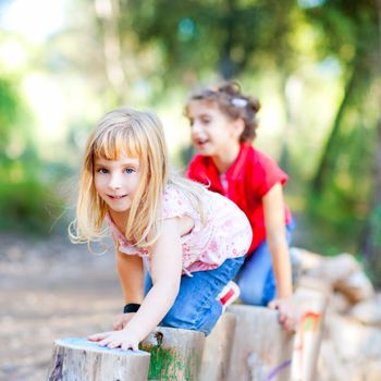 kid girls playing on trunks knee walking in forest nature