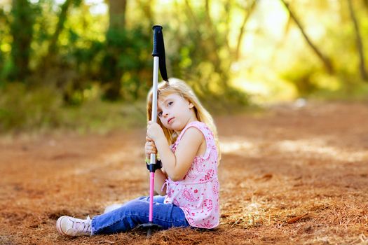 Hiking kid girl tired sitting in autumn forest outdoor