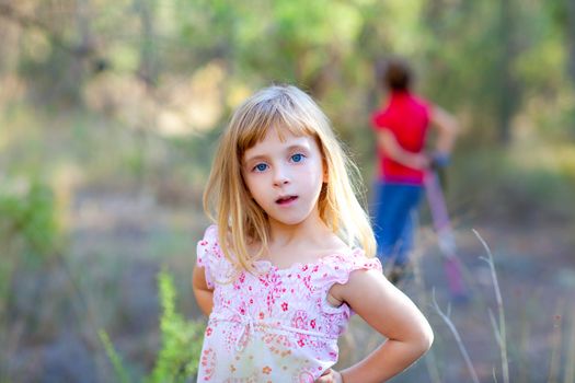 blond kid girl in forest park posing to camera