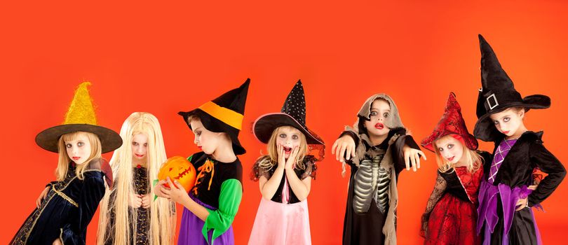 Halloween group of children girls costumes on orange background