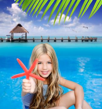 children blond girl in summer vacation tropical beach with starfish