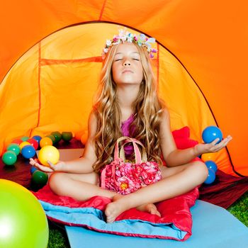 Children girl in camping tent practicing yoga open arms and balls