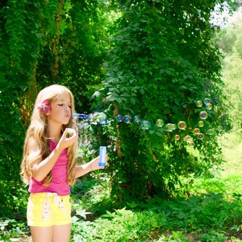 Children girl blowing soap bubbles in outdoor forest