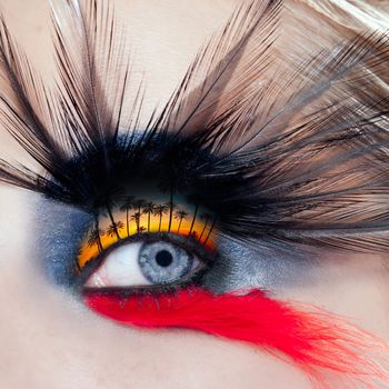 blue woman eye makeup bird inspired with black and red feathers and palm tree sunset in eyelid