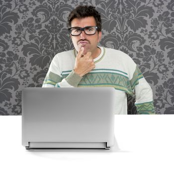 Nerd pensive man with glasses and silly expression in front a laptop computer looking for solution