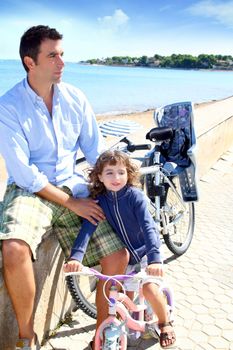 father and daughter on bicycle in beach during summer vacation