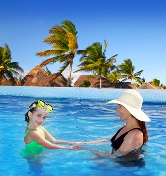 daughter and mother in swimming pool tropical location background