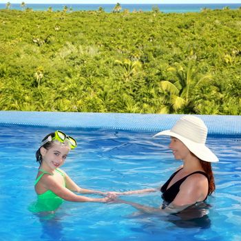 daughter and mother in swimming pool tropical location background