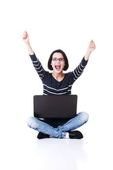 Happy young woman with fists up using her laptop, isolated on white.