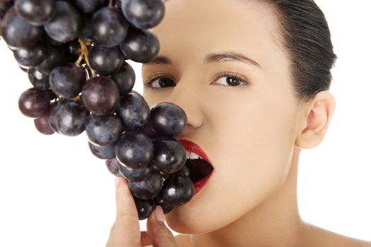 Beautiful sensual brunette eating grapes, isolated on white background